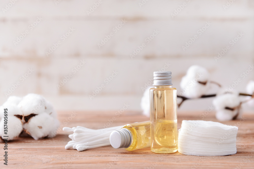 Bottles of cottonseed oil with cosmetic pads and swabs on table