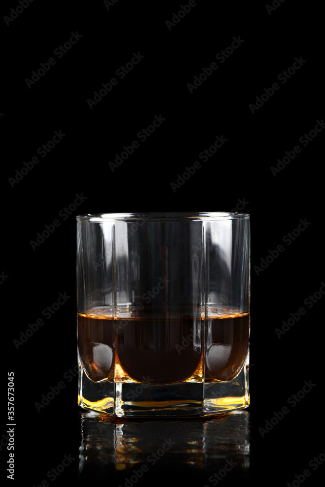 Glass of whiskey on black background