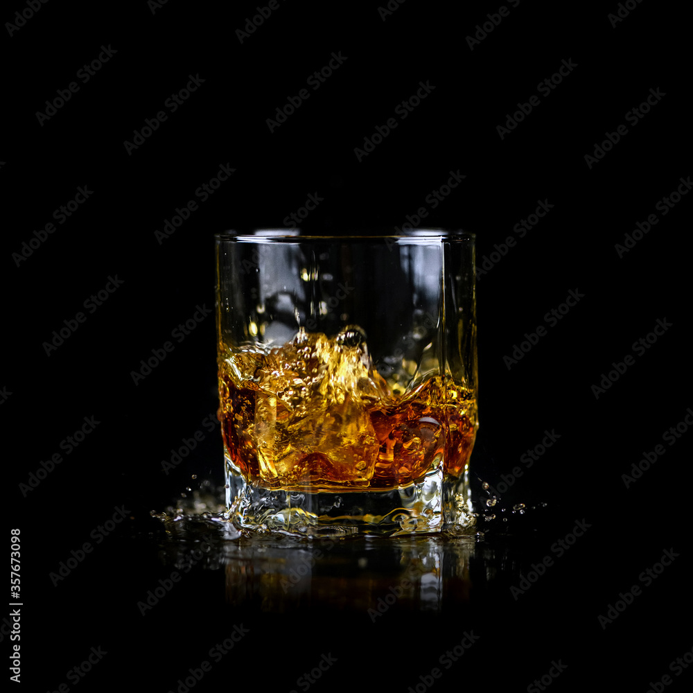 Splashing of whiskey out of glass isolated on black