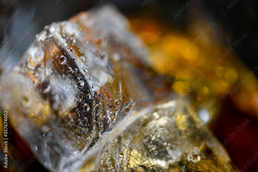 Pieces of ice cube in whiskey. Close up macro of Ice cubes in glass drink or another alcohol