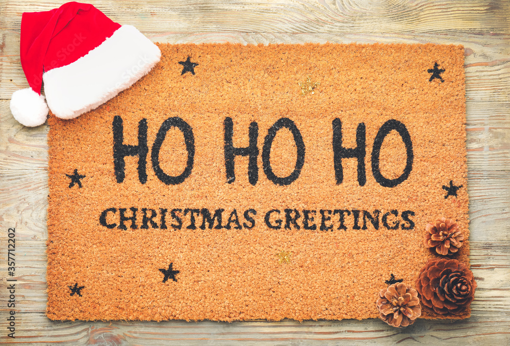 Door mat with Christmas decor on wooden background