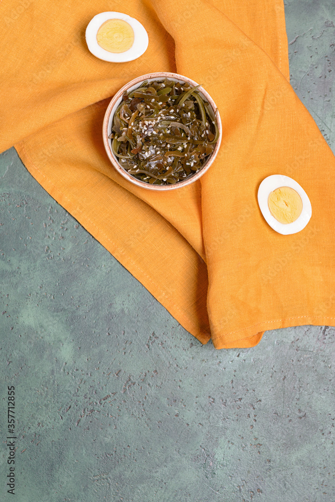 Bowl with tasty seaweed and boiled egg on color background