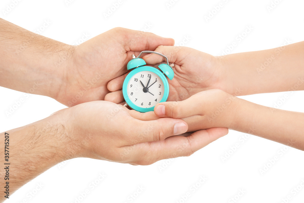 Hands of family with alarm clock on white background