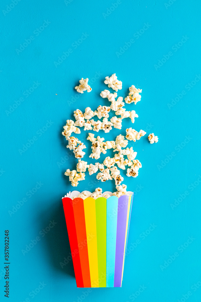 Popcorn in paper cup on blue desk top view