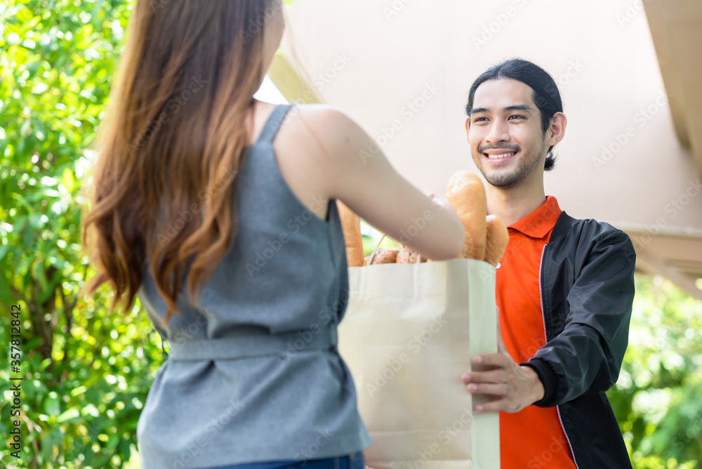 Delivery man in orange uniform pick up food for delivery at restaurant