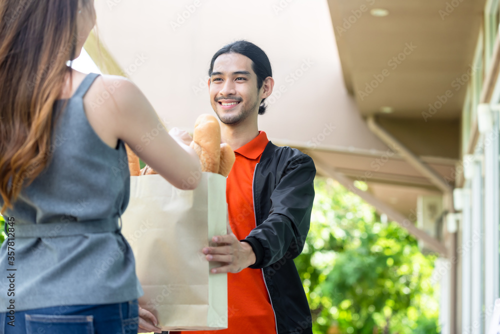 Delivery man in orange uniform pick up food for delivery at restaurant