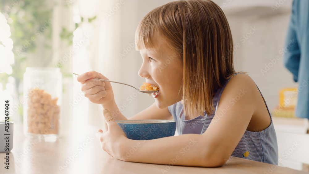 Breakfast in the Kitchen: Portrait of Adorable Little Girl Eating Healthy Granola Cereal with Milk o