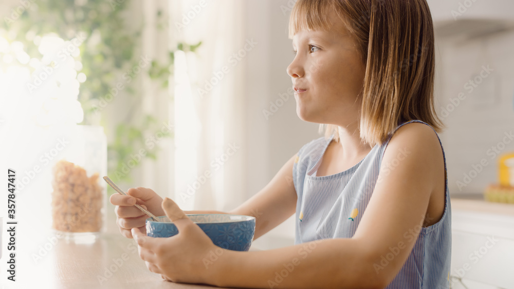 Breakfast in the Kitchen: Portrait of Adorable Little Girl Eating Healthy Granola Cereal with Milk o