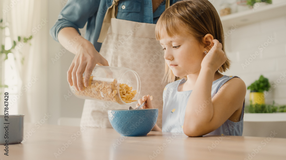 Breakfast in the Kitchen: Young Beautiful Mother Pours Cereal into Bowl, Adorable Little Daughter Pr