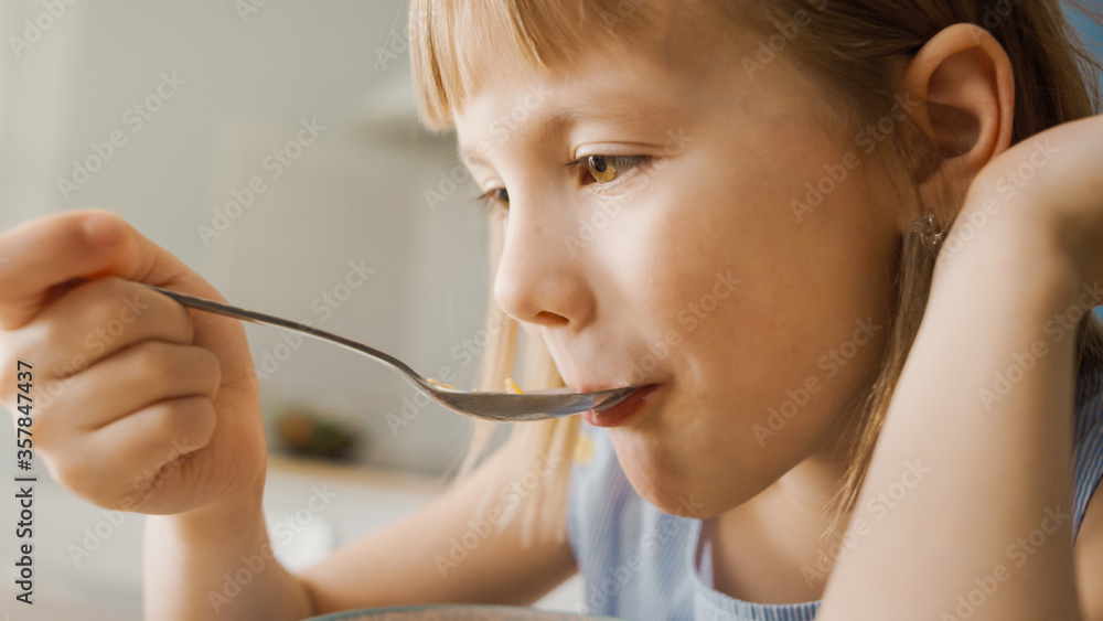 Breakfast in the Kitchen: Portrait of Adorable Little Girl Eating Healthy Granola Cereal with Milk o