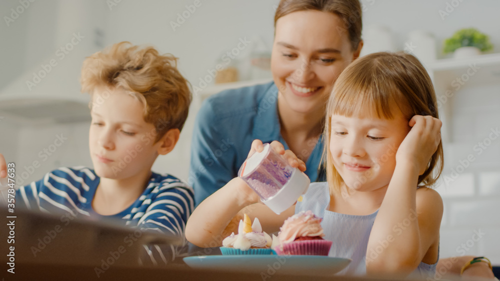 In the Kitchen: Portrait of the Young Mother and Cute Little Daughter Sprinkling Funfetti on Creamy 