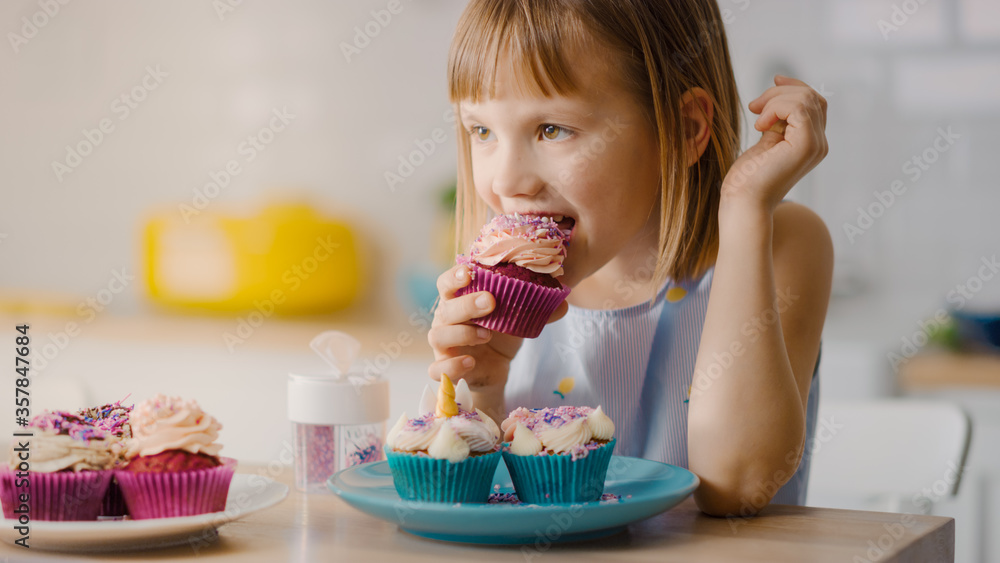 In the Kitchen: Adorable Little Girl Eats Creamy Cupcake with Frosting and Sprinkled Funfetti. Cute 