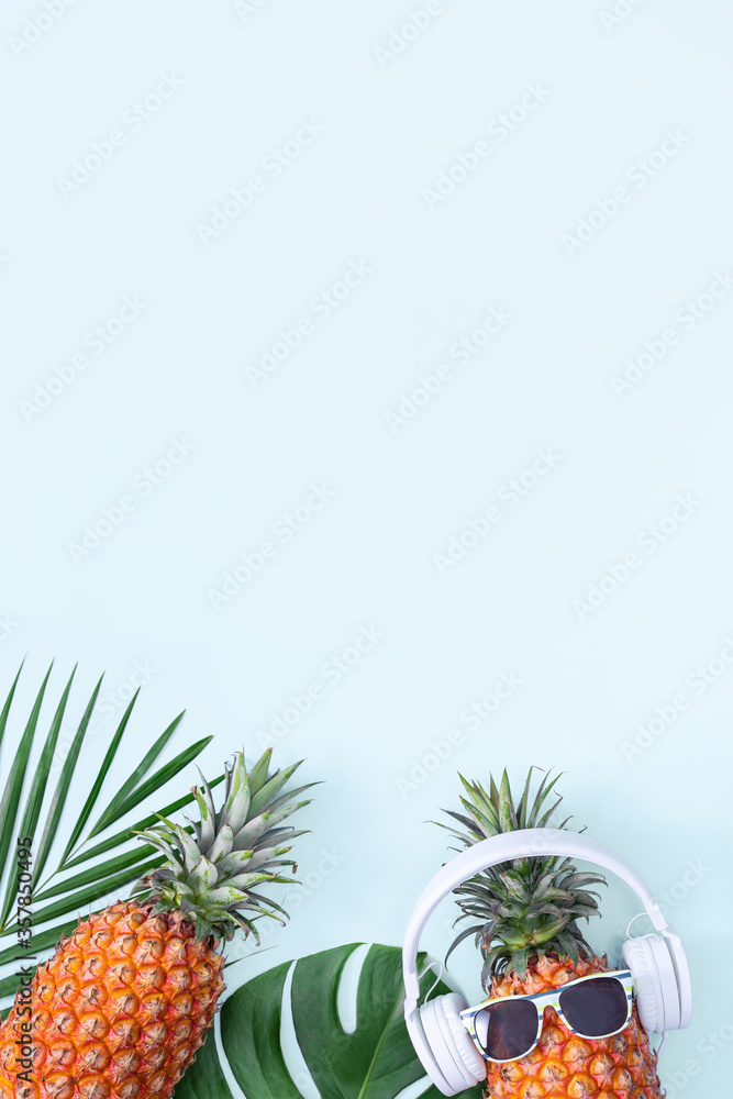 Funny pineapple wearing white headphone, concept of listening music, isolated on colored background 