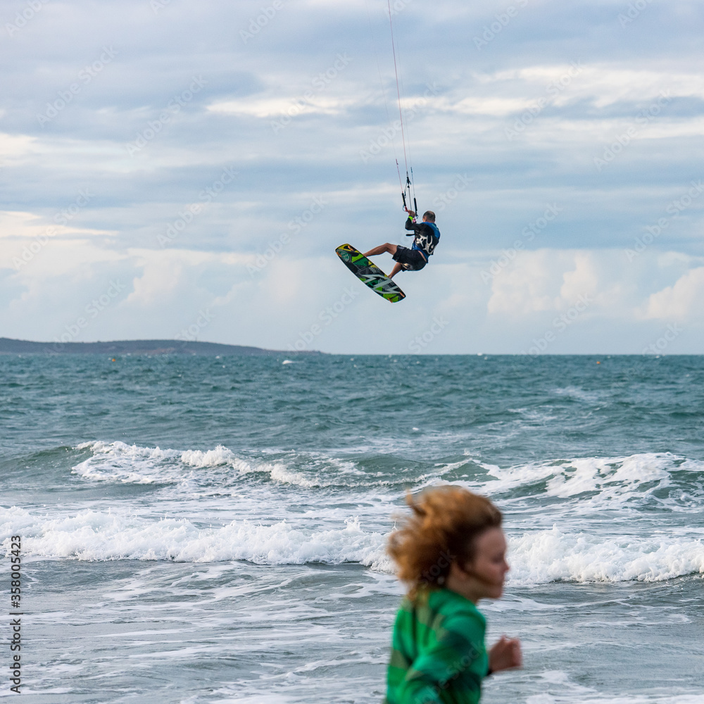 Kite surfer enjoying the waves at Tannum Sands beach with child in the foreground, Gladstone Region,