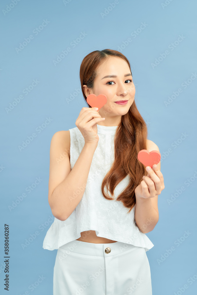 Photo of a beautiful happy young pretty woman posing isolated over blue wall background holding hear