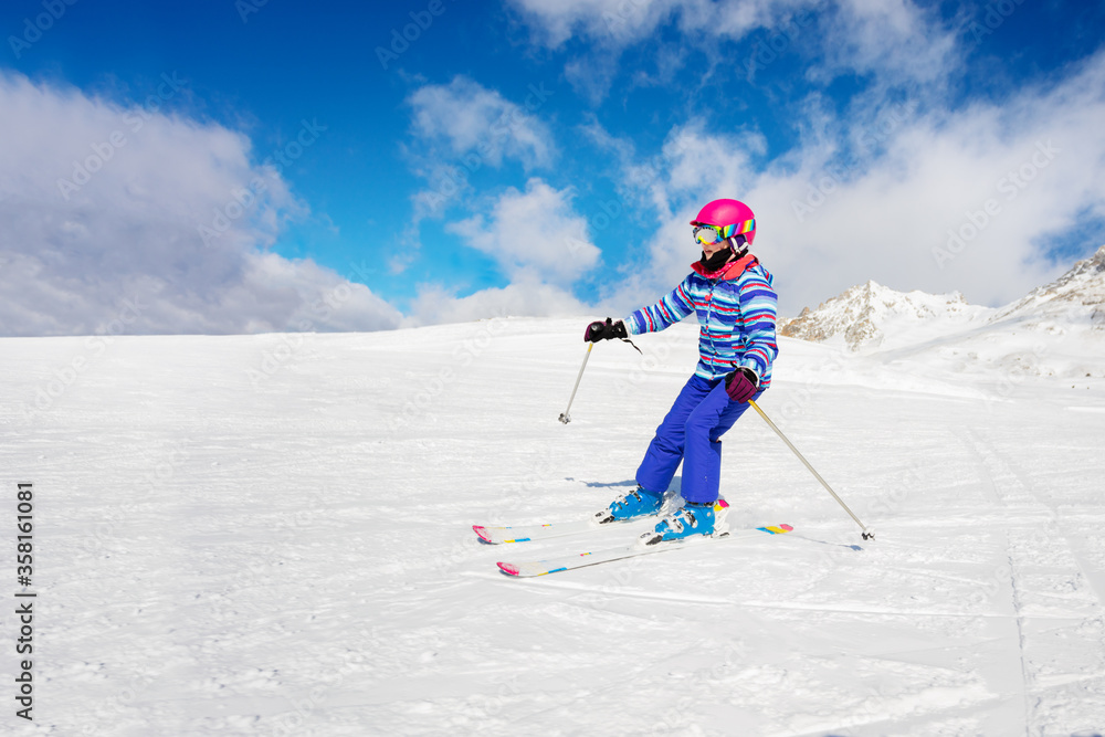 一个穿着五颜六色运动服的女孩下坡的高山滑雪肖像