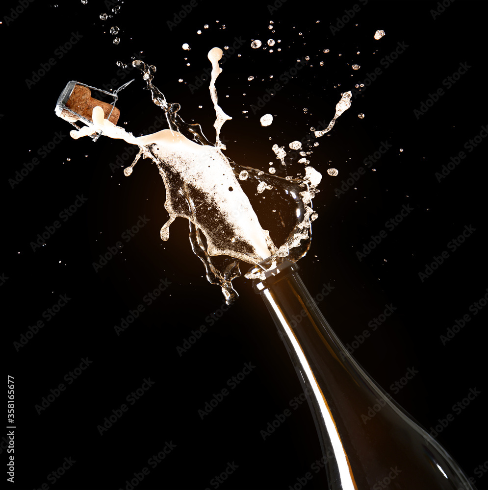 Open bottle of champagne with splash on dark background