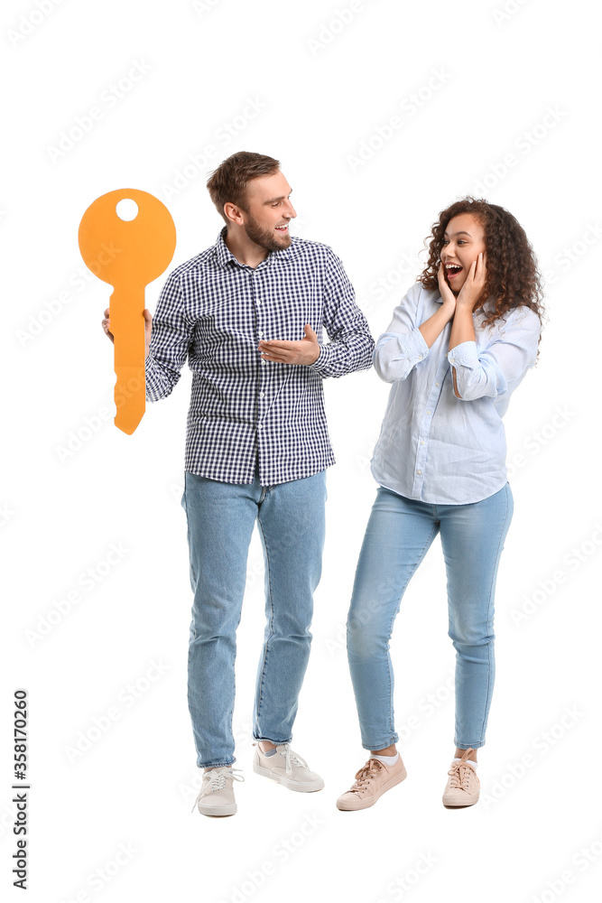 Happy young couple with big paper key on white background