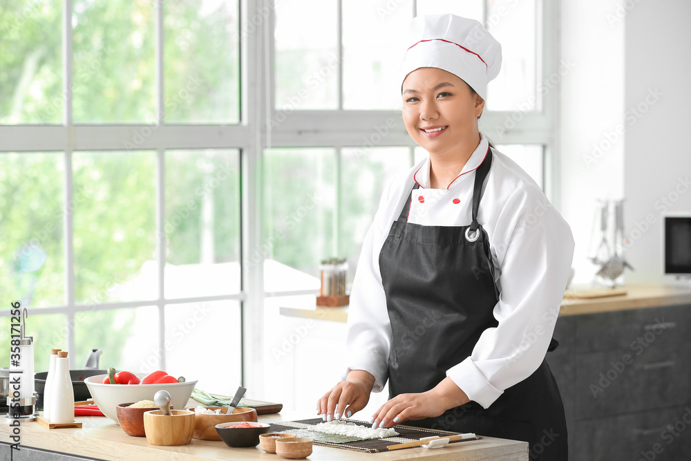 Beautiful Asian chef cooking in kitchen