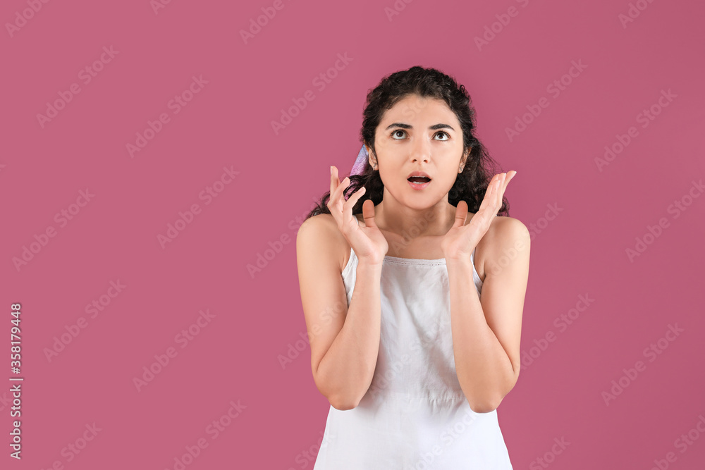 Shocked young woman on color background