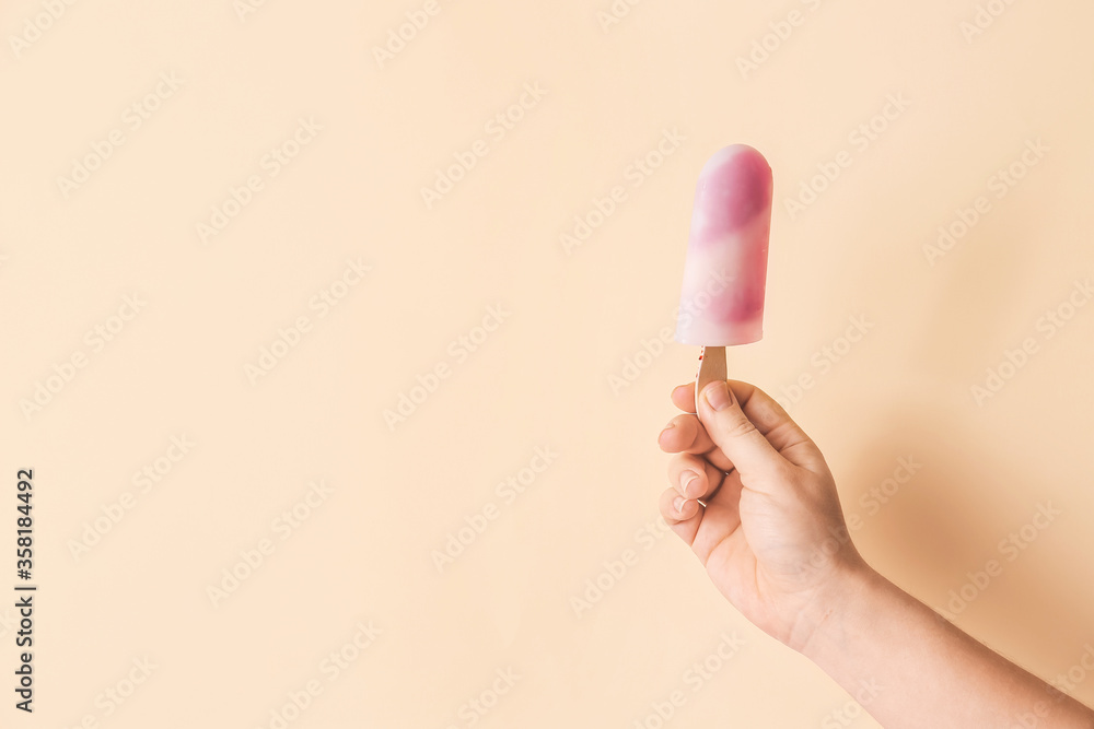 Hand with tasty strawberry ice cream on color background