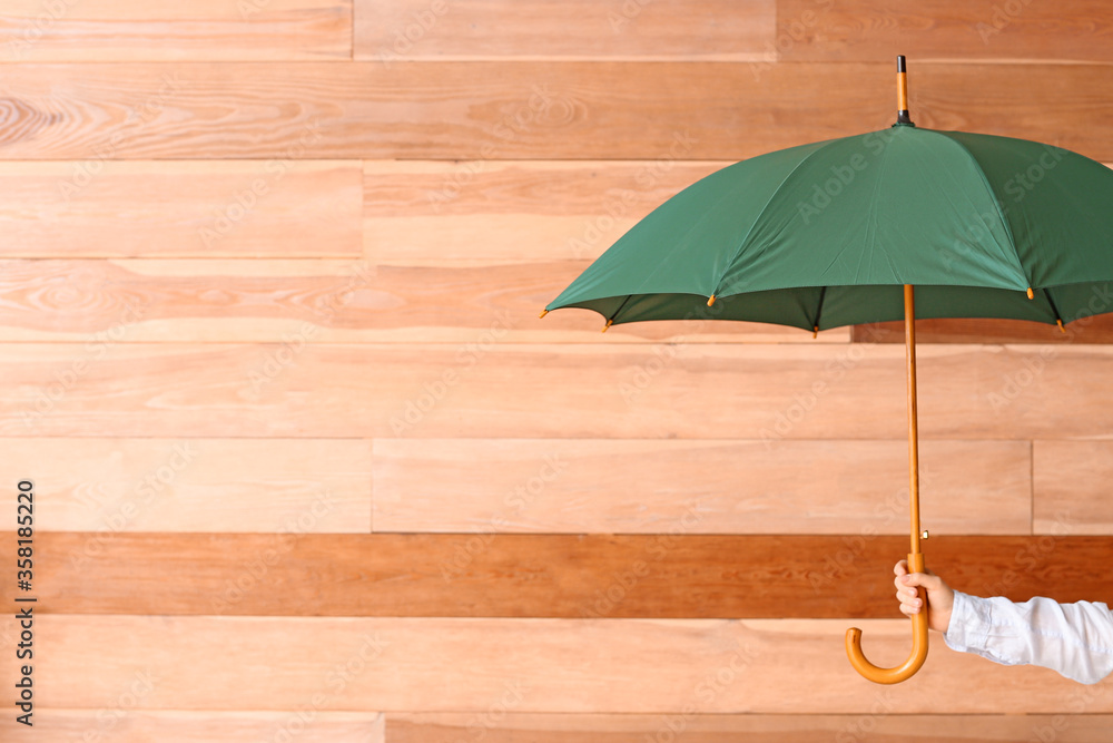 Hand with stylish umbrella on wooden background