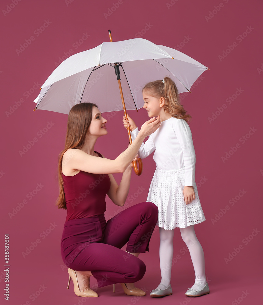 母亲和小女儿带着彩色背景的雨伞