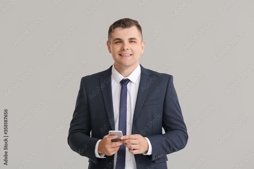 Young businessman on grey background