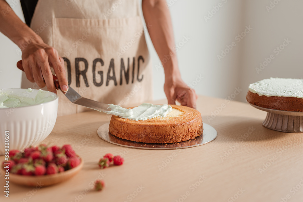 Man pastry chef put icing cream on sponge cake. Making sponge cake series