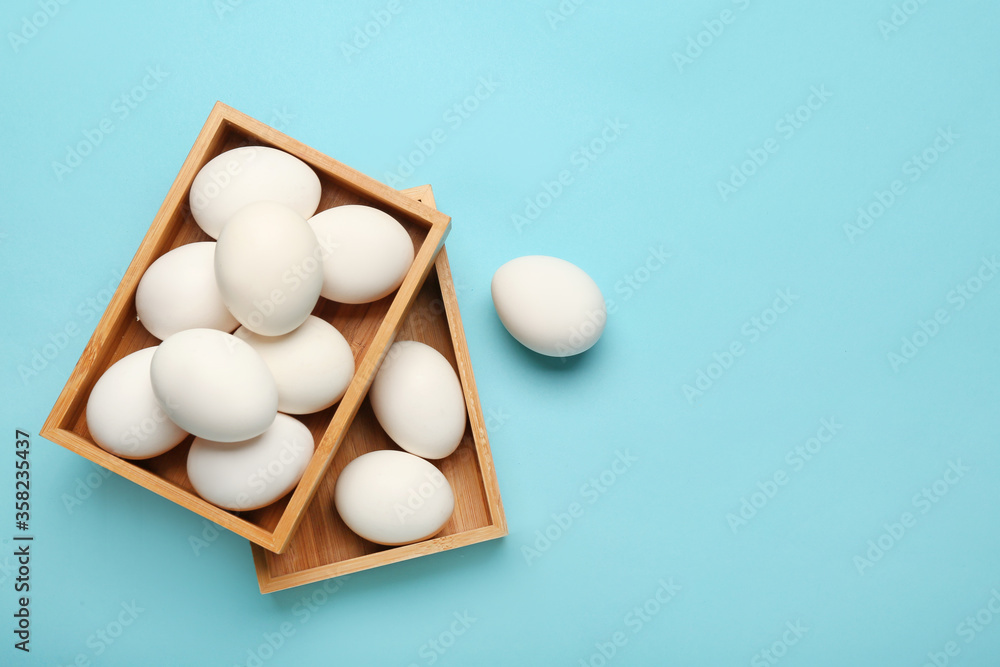 Boxes with chicken eggs on color background