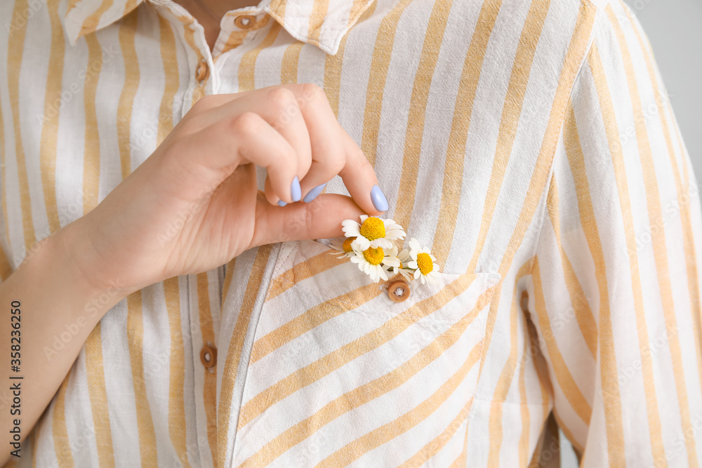 Woman with beautiful chamomiles in pocket of shirt, closeup