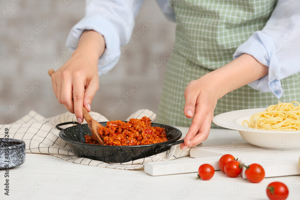 Woman cooking tasty pasta bolognese in kitchen, closeup