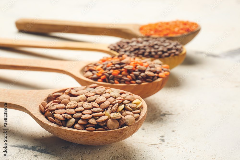 Spoons with lentils on white background