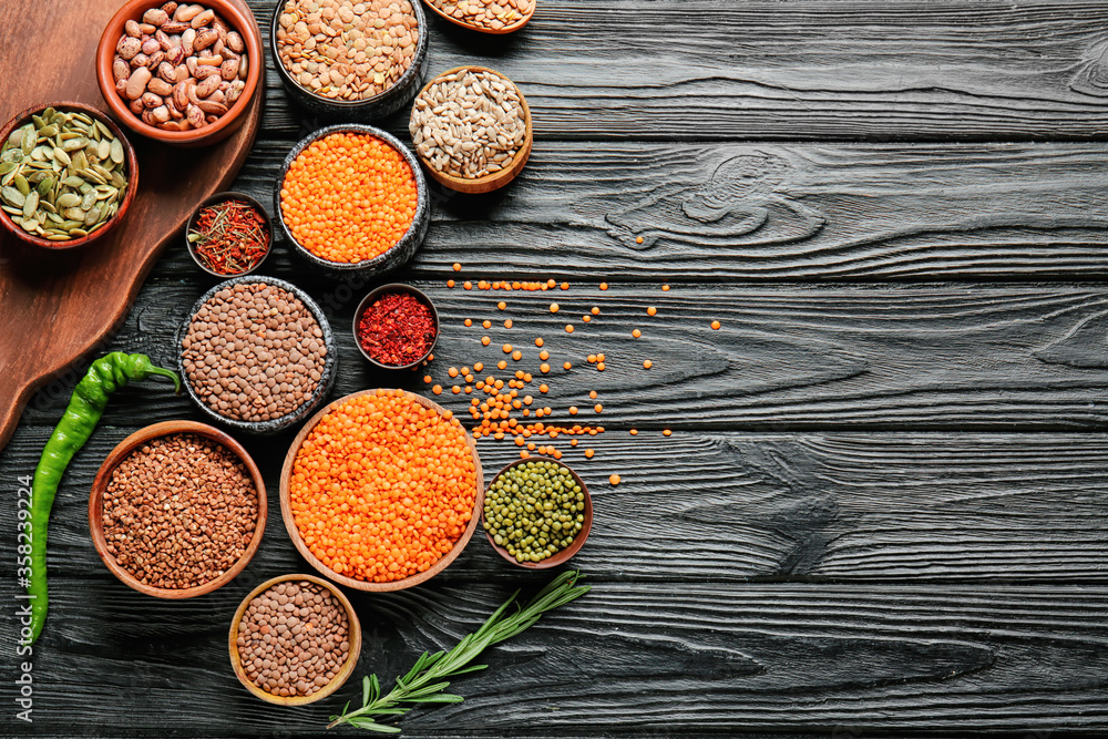 Different raw legumes with spices on table