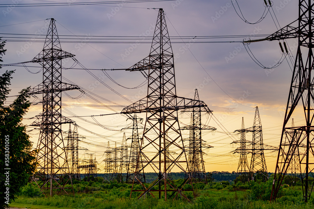 High voltage electrical substation over sunset background with transformers.