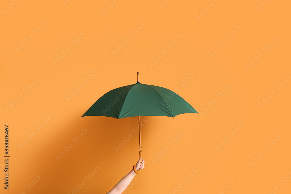 Hand with stylish umbrella on color background