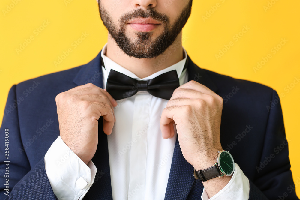 Young man in stylish suit on color background