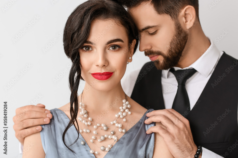 Young couple wearing stylish accessories on light background