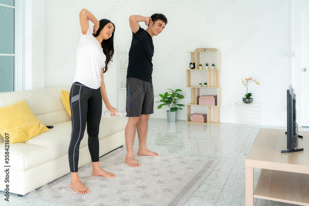 年轻的亚洲情侣一起进行高强度间歇训练，在家看电视，男人和女人