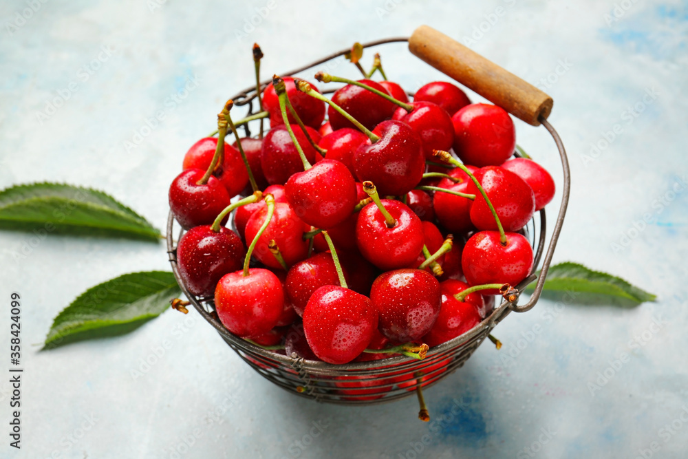 Basket with sweet cherry on color background