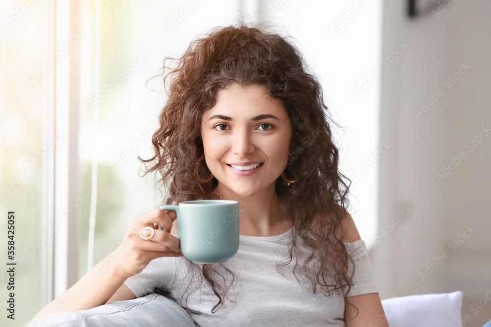 Beautiful young woman drinking hot tea at home