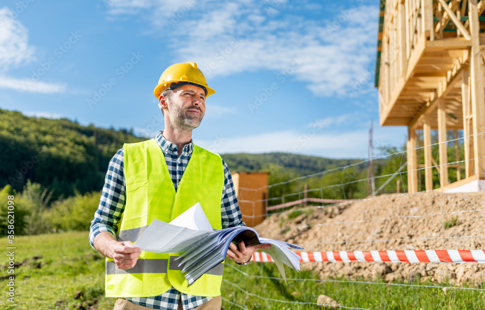 Construction engineer or architect control a construction site of wood frame house