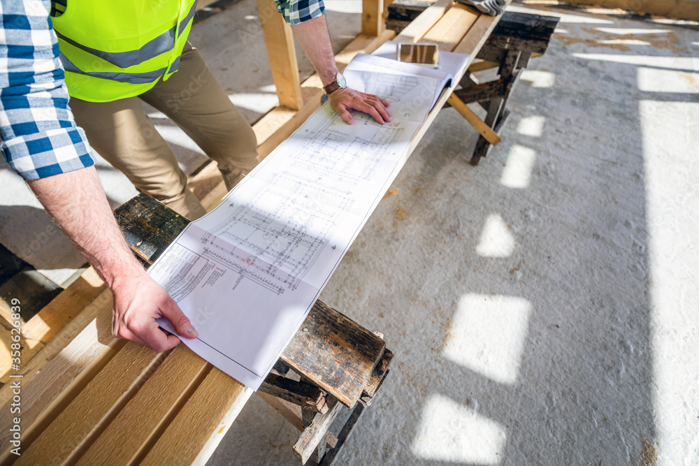 Architect or engineer on construction site looking at blueprints of building house, close up