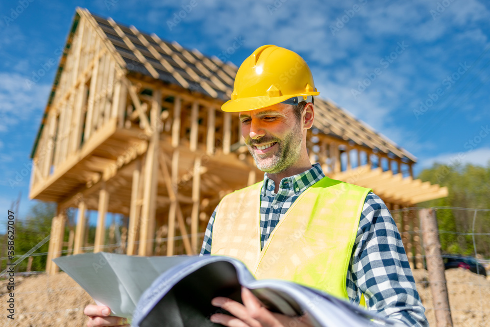 Architect on building site looking at blue prints house plans