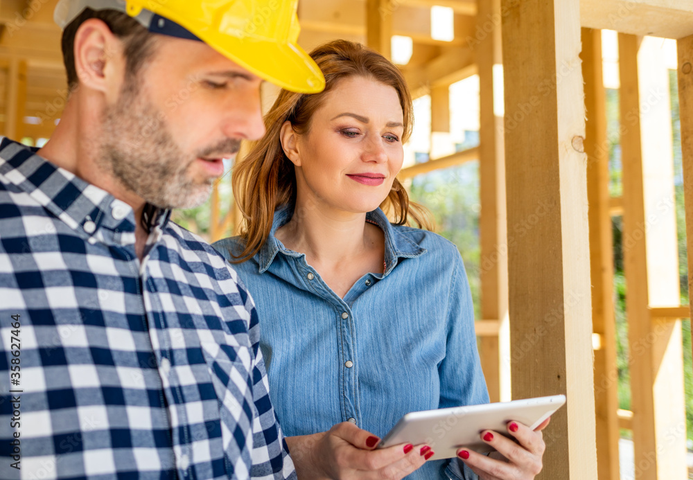 Architect or engineer with blueprints meeting with owner of building house on construction site