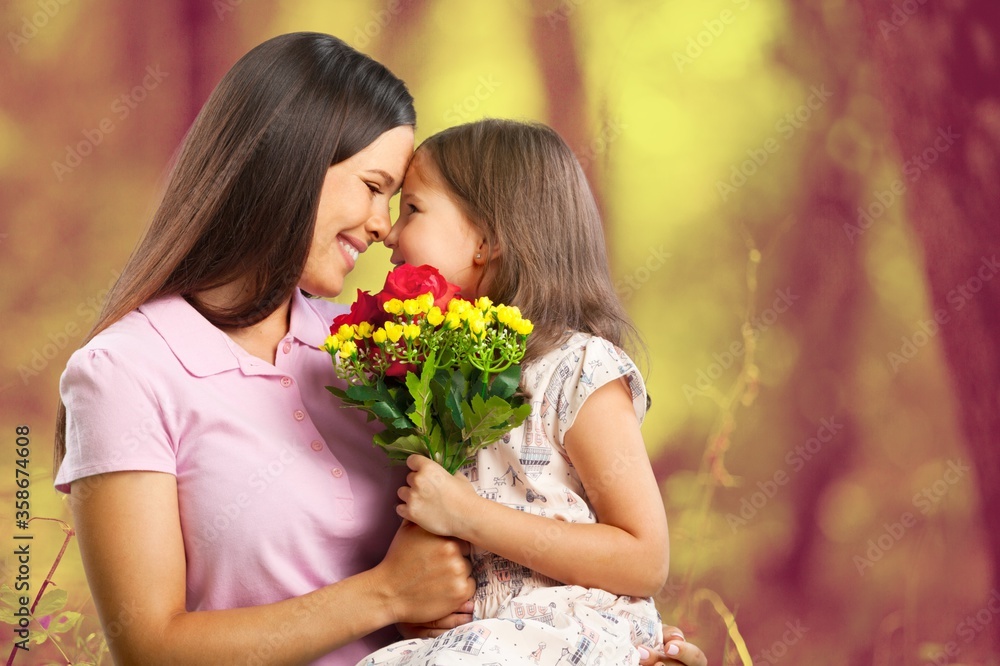 Mother and daughter with bouquet of flowers on blurred background.