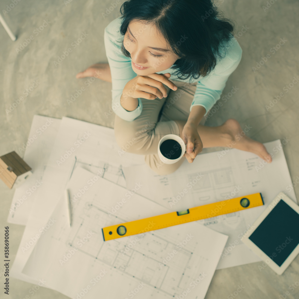 Female architect working at home.She looking blueprints.