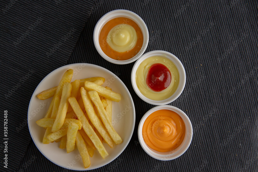 French fries on a wooden plate on a black fabric floor