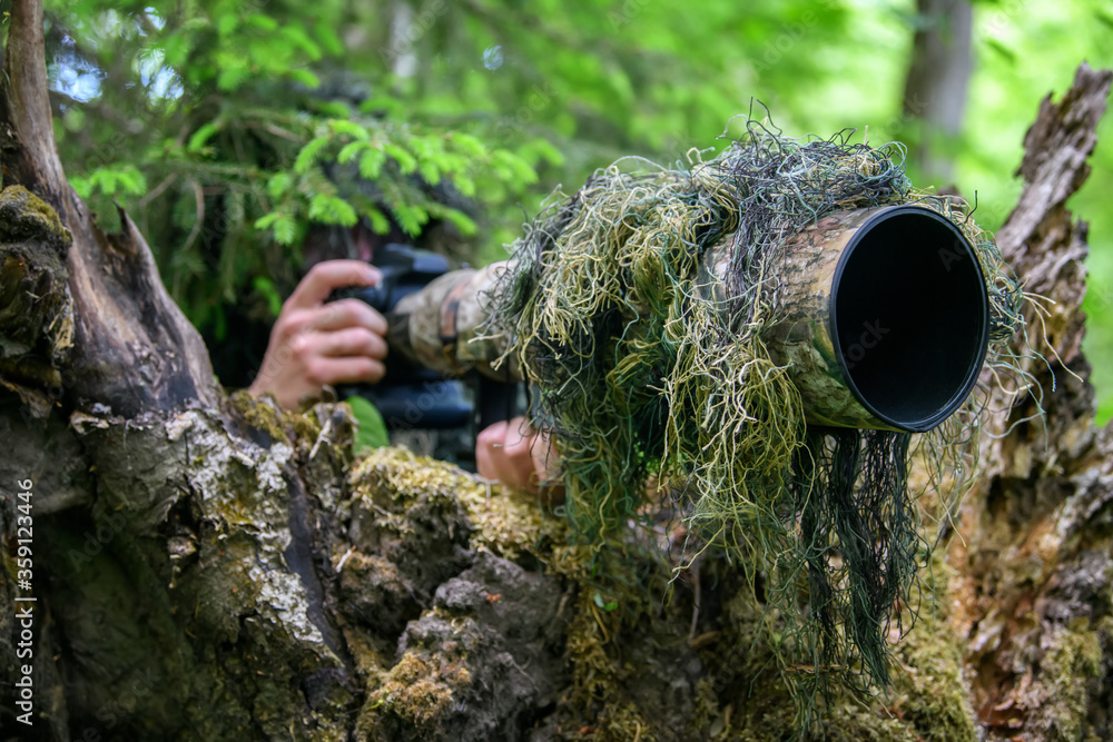 Wildlife photographer in the summer ghillie camouflage suit