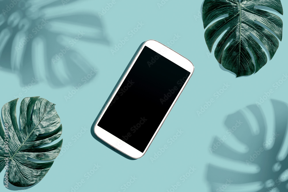 Smartphone with tropical monstera leaves and shadow - flat lay